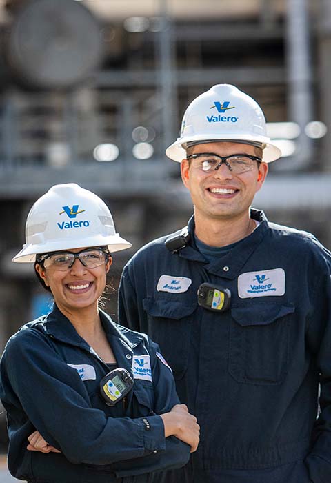 Valero refinery colleagues stand together in front of equipment.