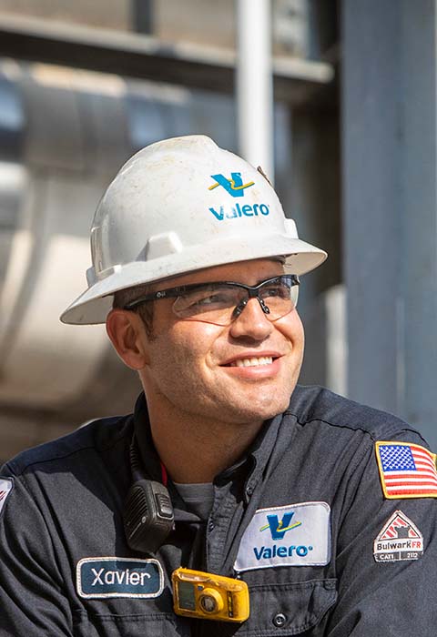 A man wears a Valero hard hat and Nomex gear.