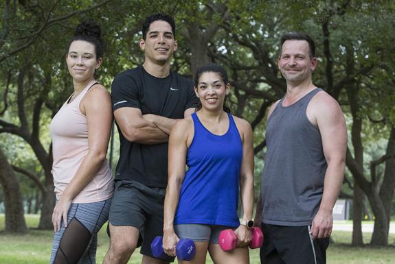 Four Valero employees in athletic gear pose outdoors with workout equipment