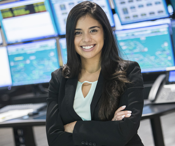 Woman smiling in front of screens with arms folded
