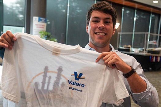Young Man holding up a t-shirt that says "Valero 2020 Intern"