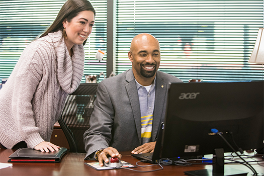 A man and woman looking at a computer screen together