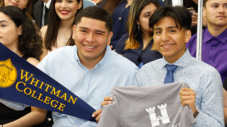 High school students part of the YESS program hold college pennants and celebrate their college goals