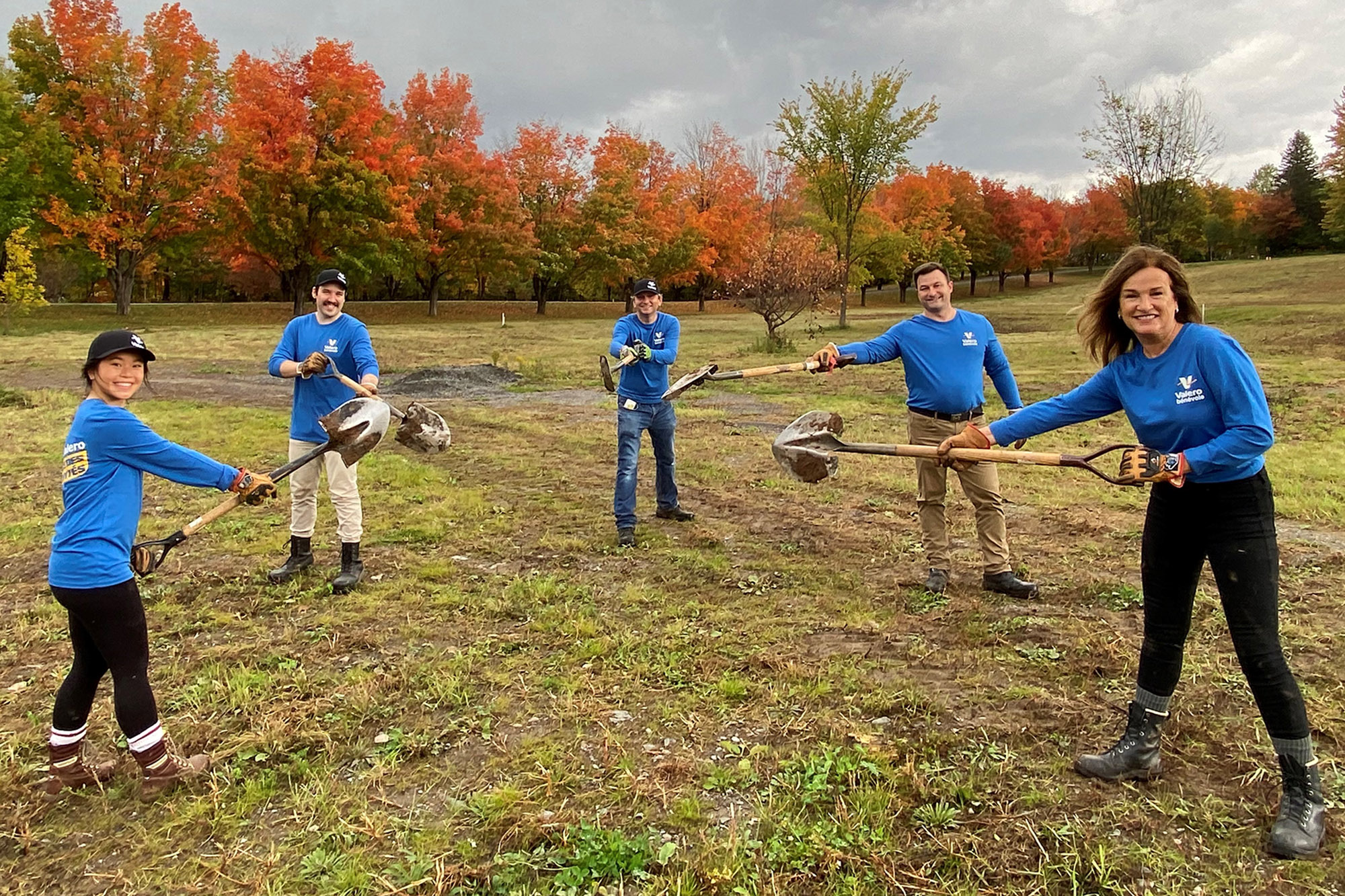 Volunteers hold shovels in a field