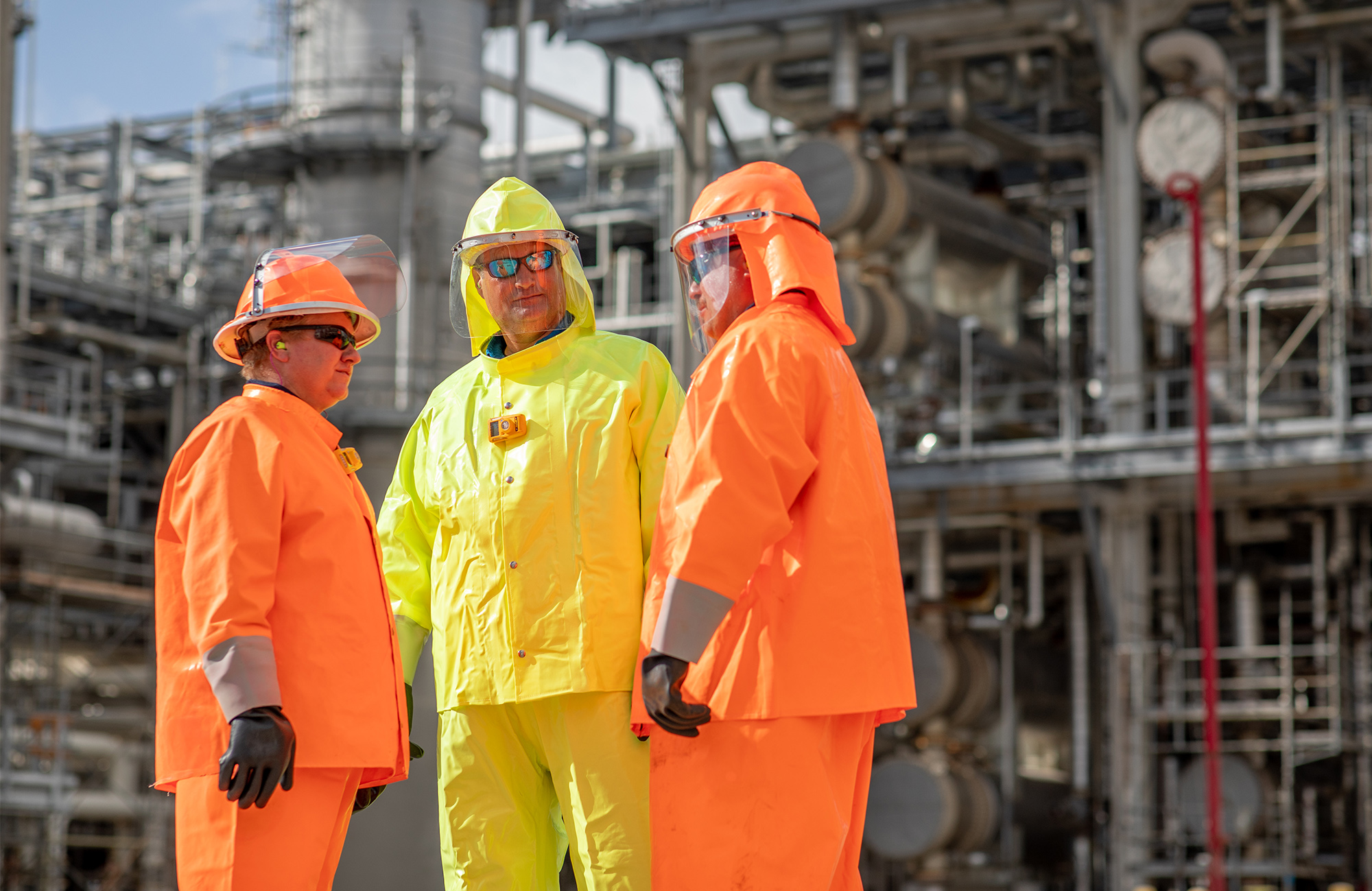 Refinery employees wearing bright colored safety uniforms