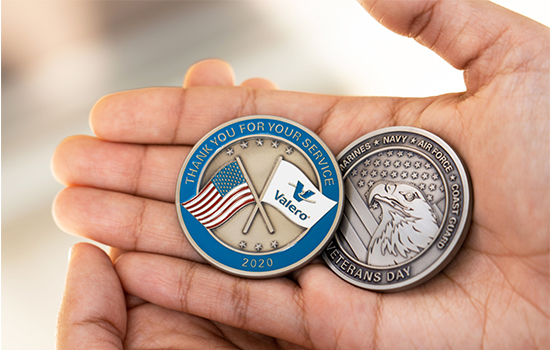 A hand holding two Valero Veteran Coins