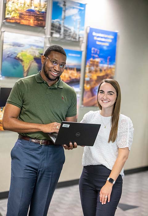 Two Valero employees review work on a laptop together.