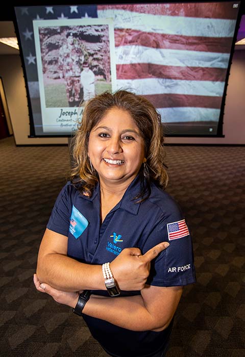 A veteran and Valero employee smiles and points to an American flag on her sleeve.