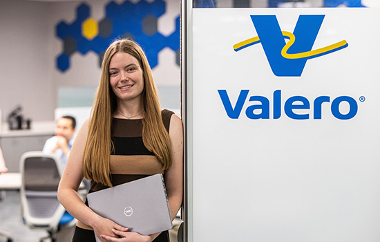 A Valero employee holds her laptop in front of a conference room.