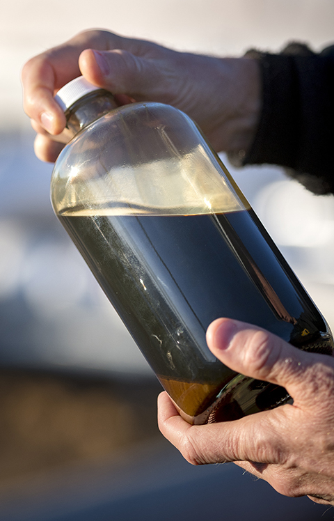 Valero employee holding crude oil in container