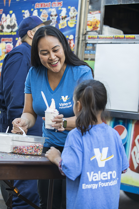 Valero Volunteer handing ice cream to young girl