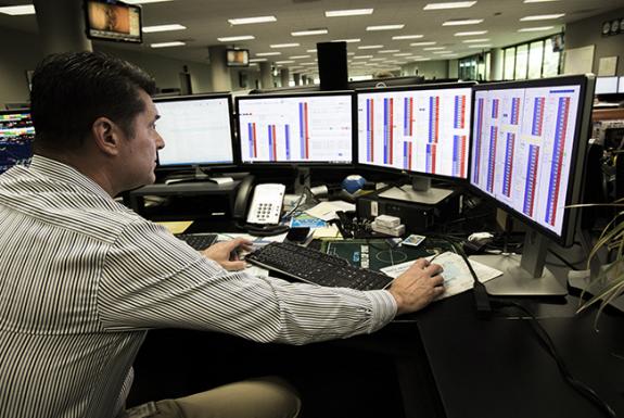 Employee surveys multiple monitors in sync from his desk
