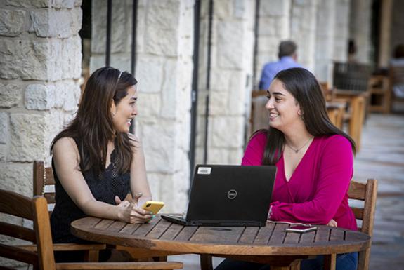 Two women talking during an interview from an outdoor patio table.