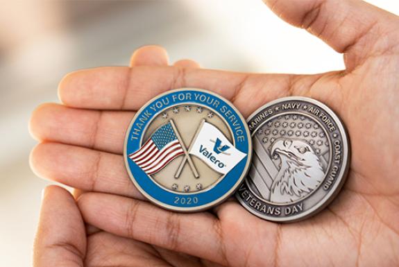 A hand holding two Valero Veteran Coins
