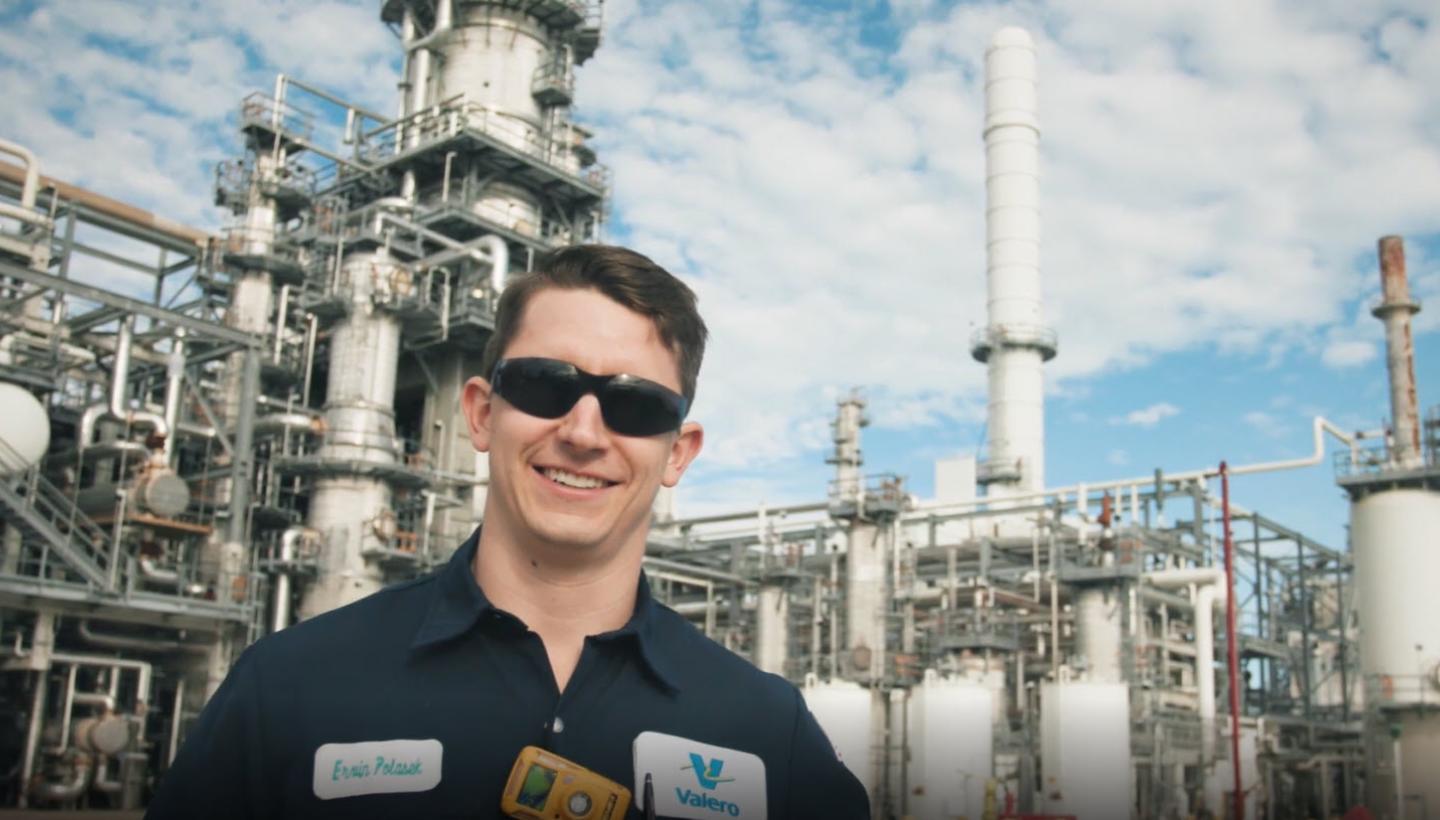 Smiling Operator in front of a refining unit, as a screen shot from video