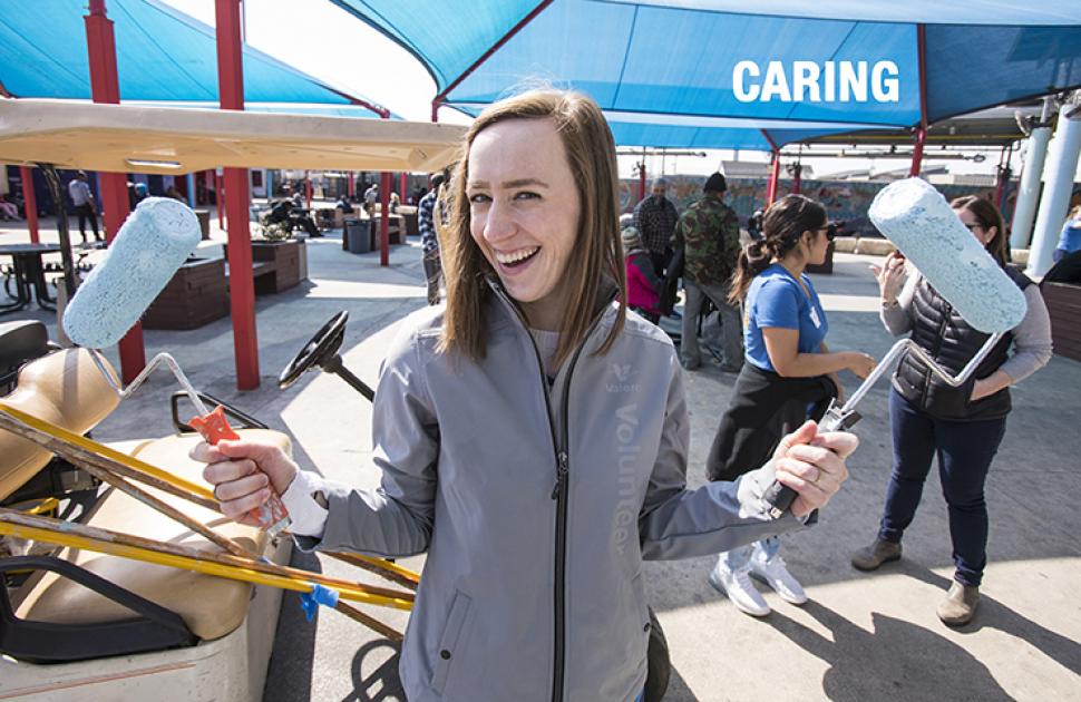 Employee volunteer with paint rollers smiling at an event