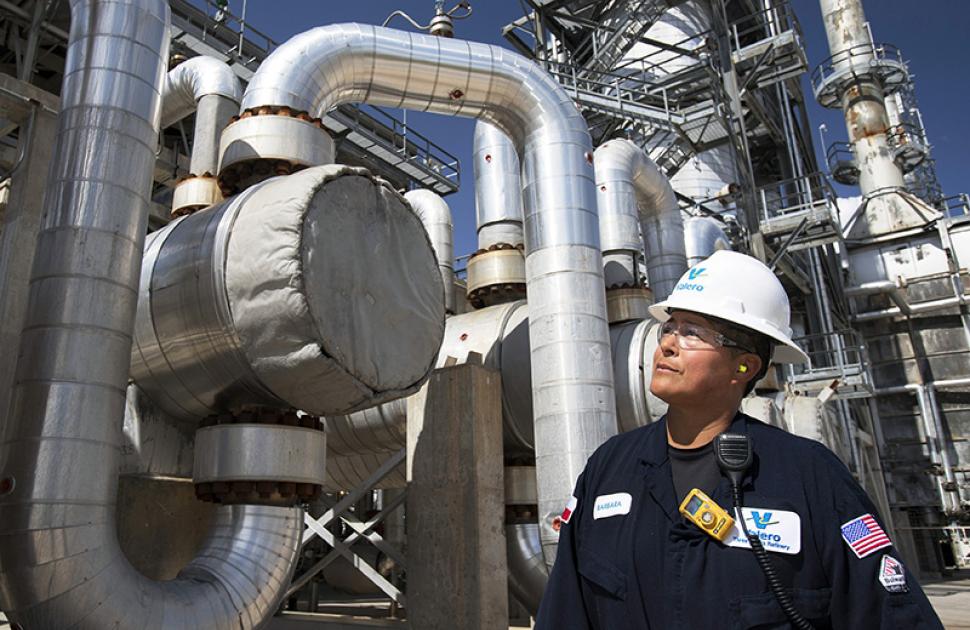 Operator walking near large-scale refining units and looking up at them