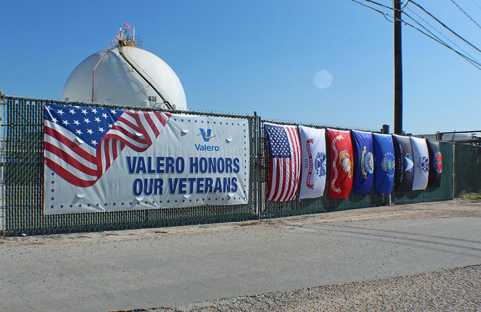 Photo of Military Flags and a flag that says "Valero Honors Our Veterans" outside of the Houston Refinery