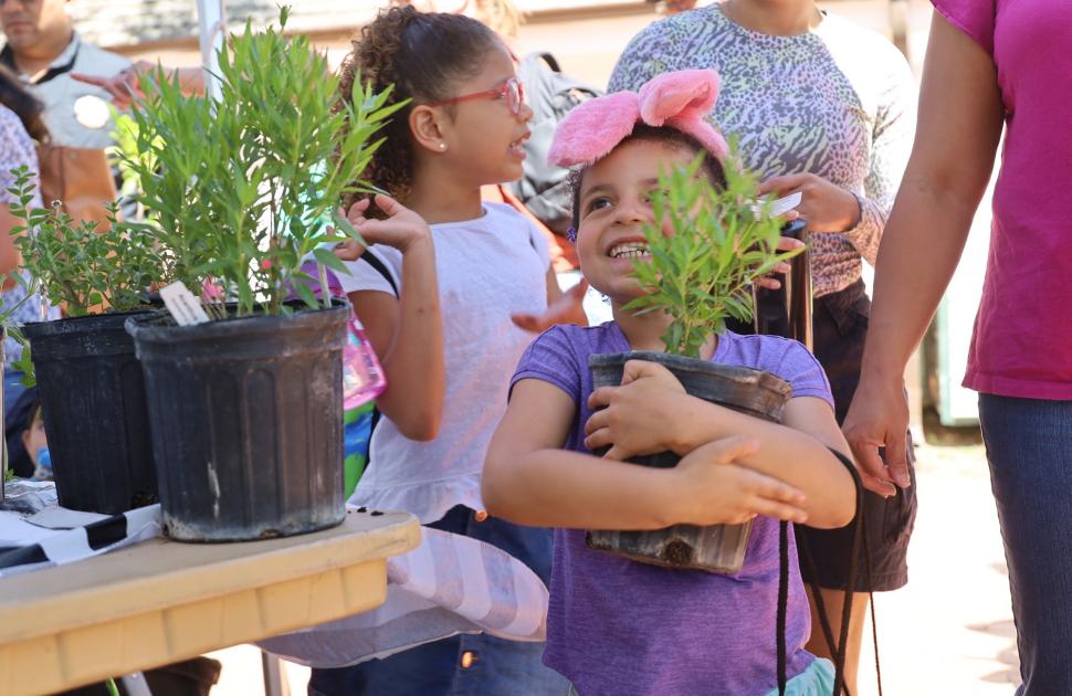 Young girl excitedly holds new plant, donated by Valero