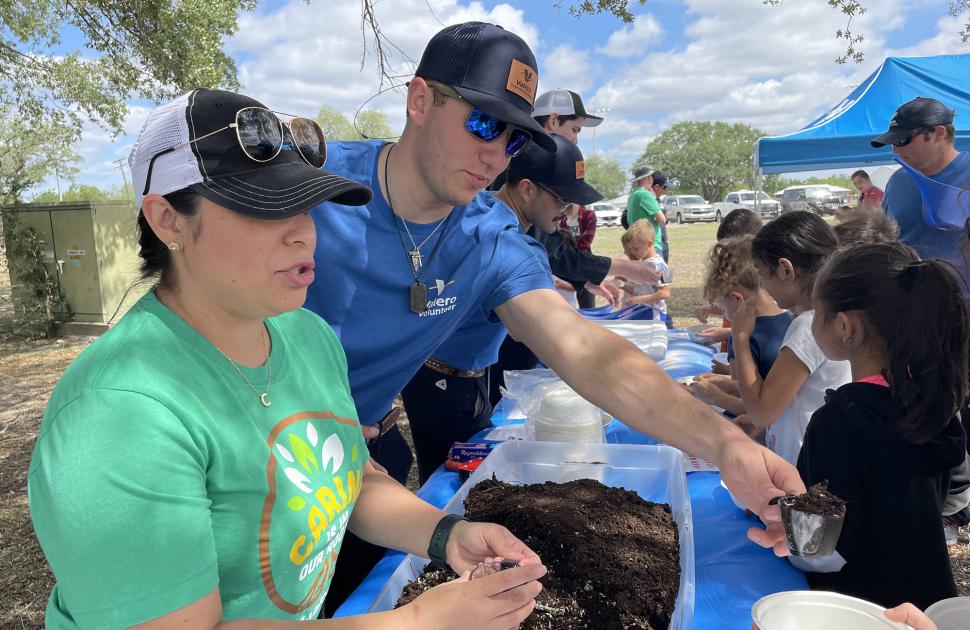 Valero volunteers hand out dirt to children for earth day event