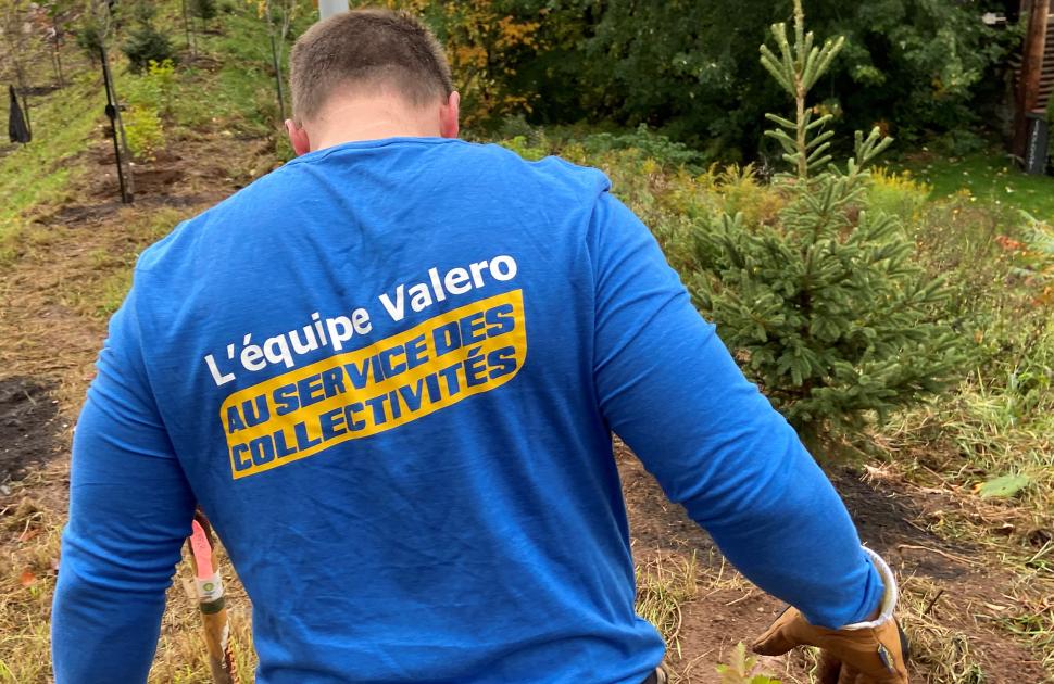 Valero Volunteer faces away from the camera, displaying French "Valero Volunteers, Fueling our Communities" shirt