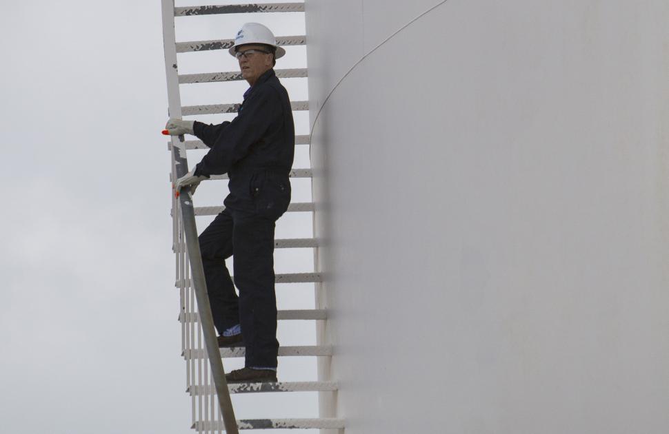 Person climbing ladder at McKee Refinery
