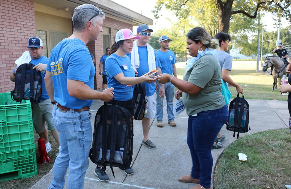 Valero volunteers at a public park give backpacks filled with essentials to those in need.