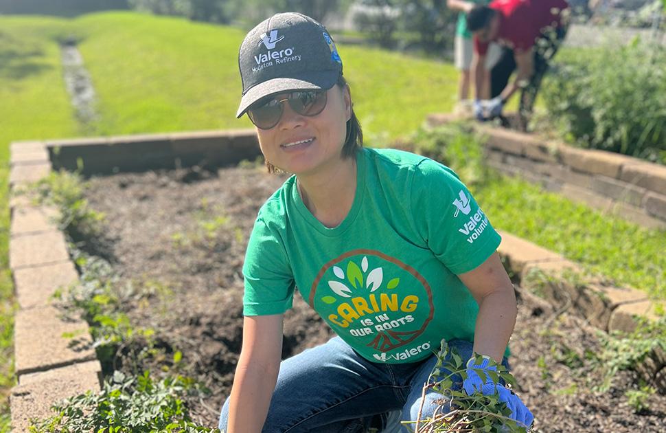 A Valero volunteer pulls weeds in a community garden.