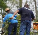 Volunteers clear debris off a house affected by a hurricane.