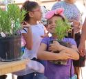 Young girl excitedly holds new plant, donated by Valero