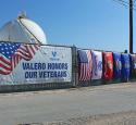 Photo of Military Flags and a flag that says "Valero Honors Our Veterans" outside of the Houston Refinery