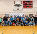 Valero volunteers pose together for a photo beneath a basketball hoop inside a gymnasium.