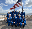 Group of Corpus Christi Interns with American flag behind 