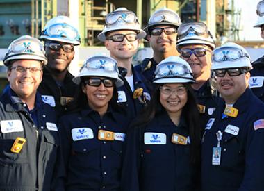 Operations team grouped together smiling in front of refining units
