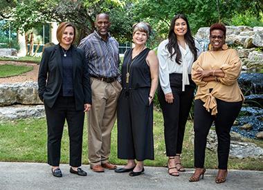 5 individuals standing and smiling outdoors
