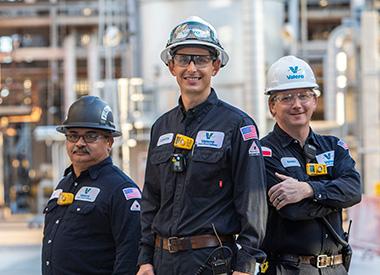 Three Valero employees stand together at a refinery.
