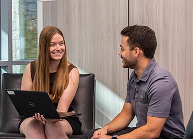 Two coworkers sit with a laptop for an impromptu meeting.