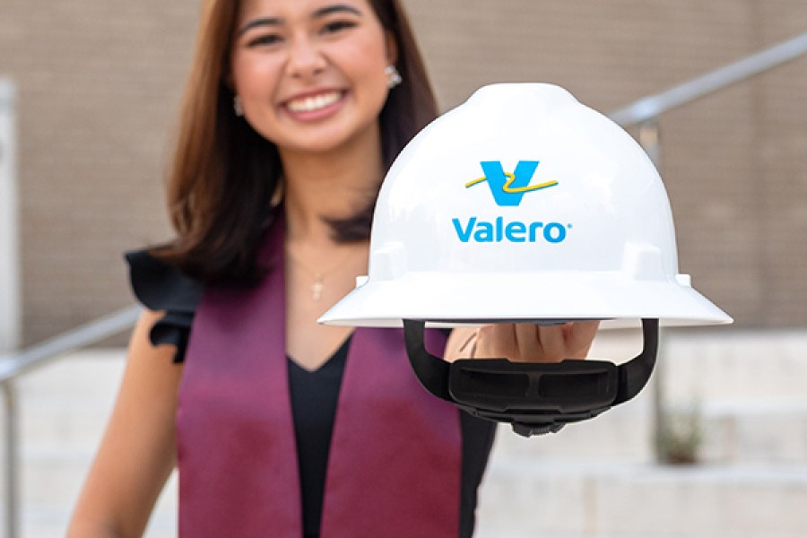 A recent college graduate holds a Valero hard hat.