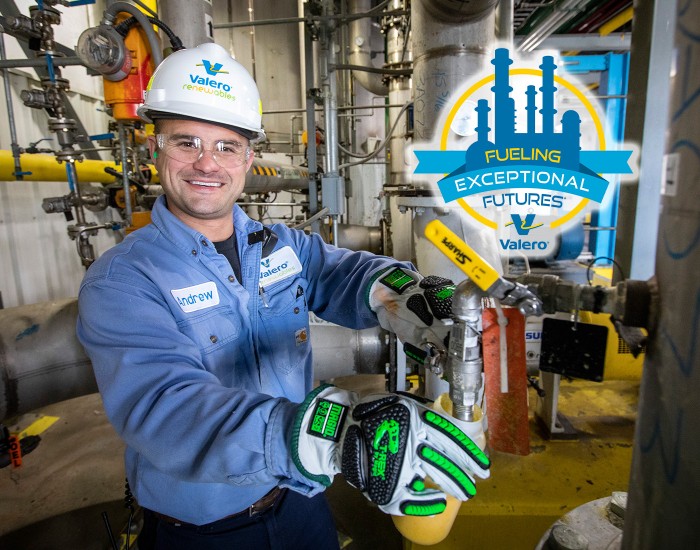 A Valero refinery employee smiles in front of equipment. To his left is Valero's Fueling Exceptional Futures logo, featuring a silhouette of a refinery in blue, surrounded by a thin yellow circle. Within the circle is a blue banner with blue, yellow and white text that reads FUELING EXCEPTIONAL FUTURES. Beneath this is the Valero logo, accompanied by the Valero company name.
