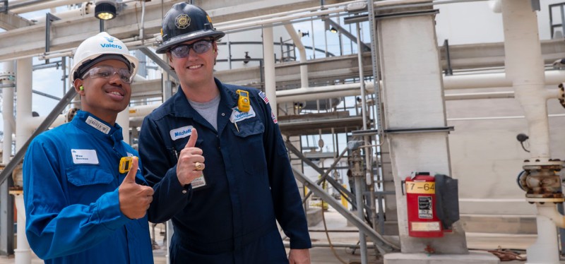 Two Summit participants giving thumbs up at a refinery.